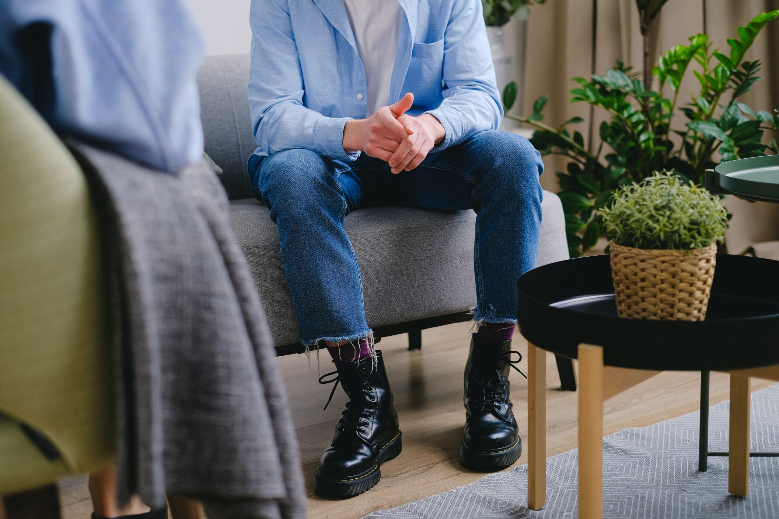 Client in blue shirt, sitting on a couch, in a Counselling session.